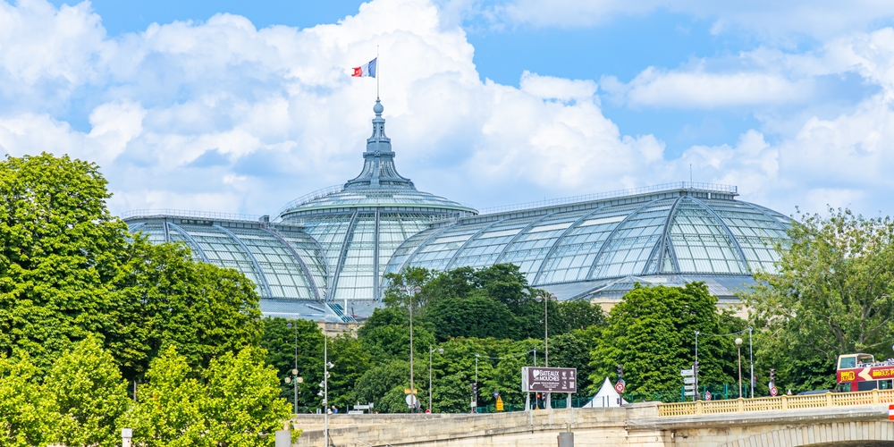 Vue extérieure du Grand Palais à Paris avec son architecture en verre et le drapeau français au sommet.