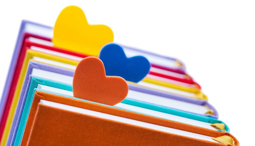 Des livres colorés avec des marque-pages en forme de cœur.