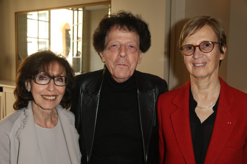 Trois personnes posent ensemble lors d’un événement dans un cadre intérieur élégant.
