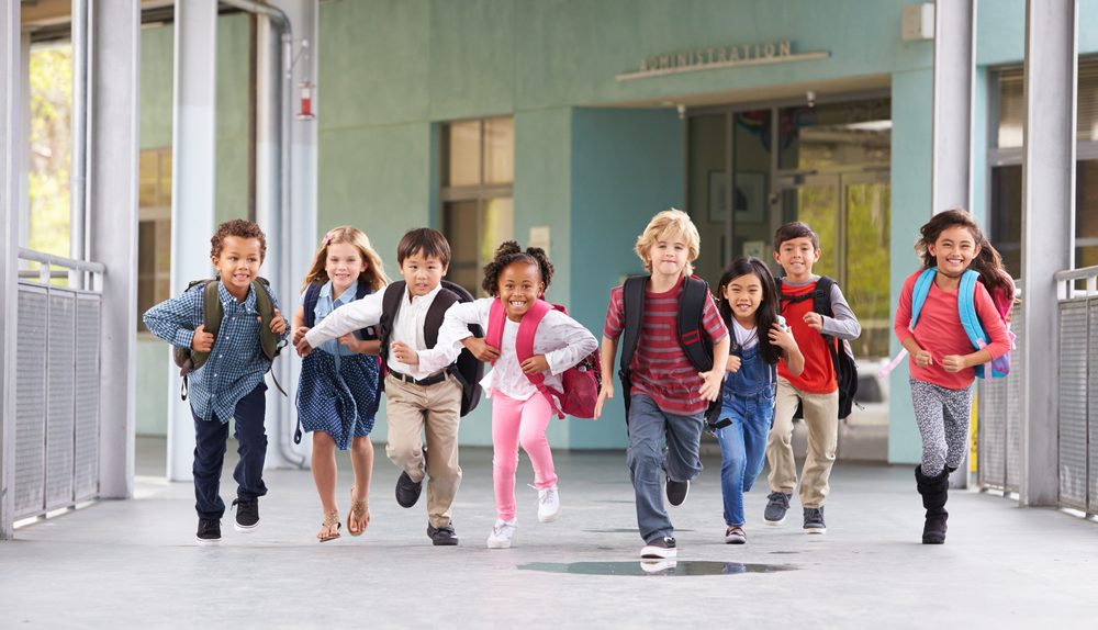 Des enfants souriants faisant leur rentrée scolaire avec leurs cartables