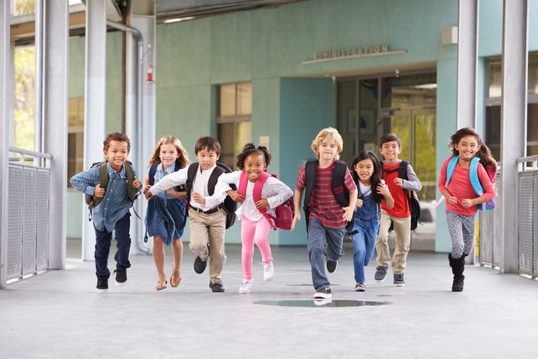 Des enfants souriants faisant leur rentrée scolaire avec leurs cartables