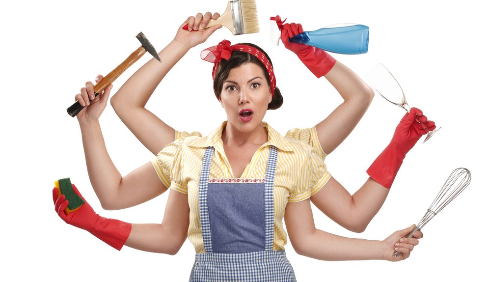 Femme multitâche tenant plusieurs objets ménagers et outils.