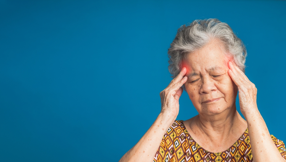 Femme âgée se tenant les tempes avec une expression de douleur.
