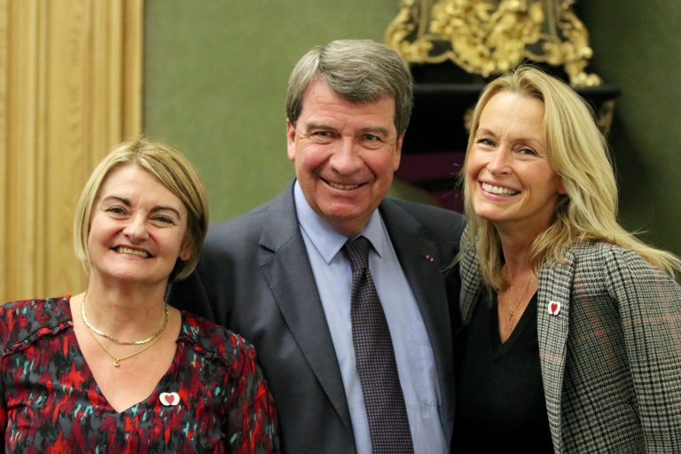 Trois personnes souriantes lors d’un événement officiel.