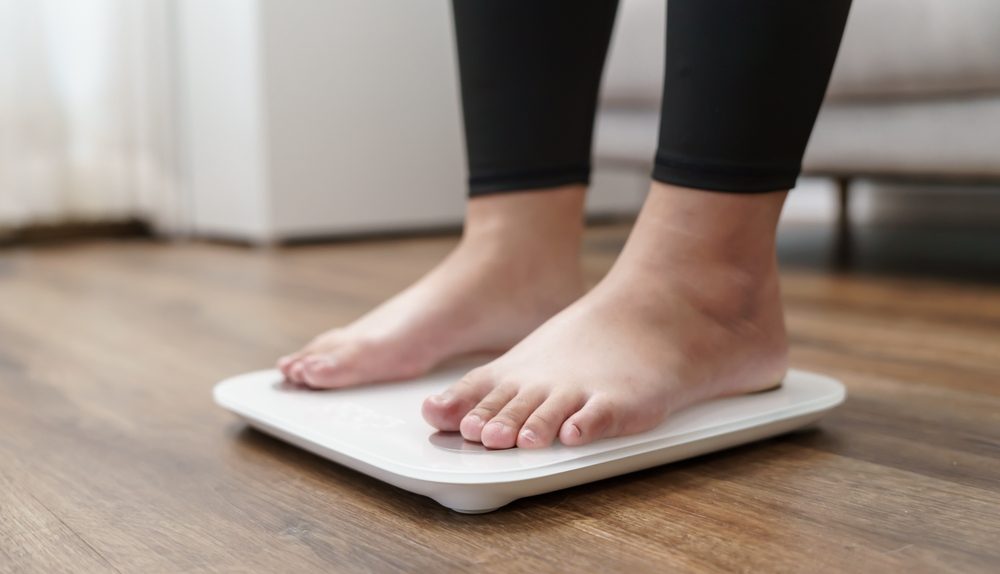 Personne debout sur une balance dans une pièce intérieure.