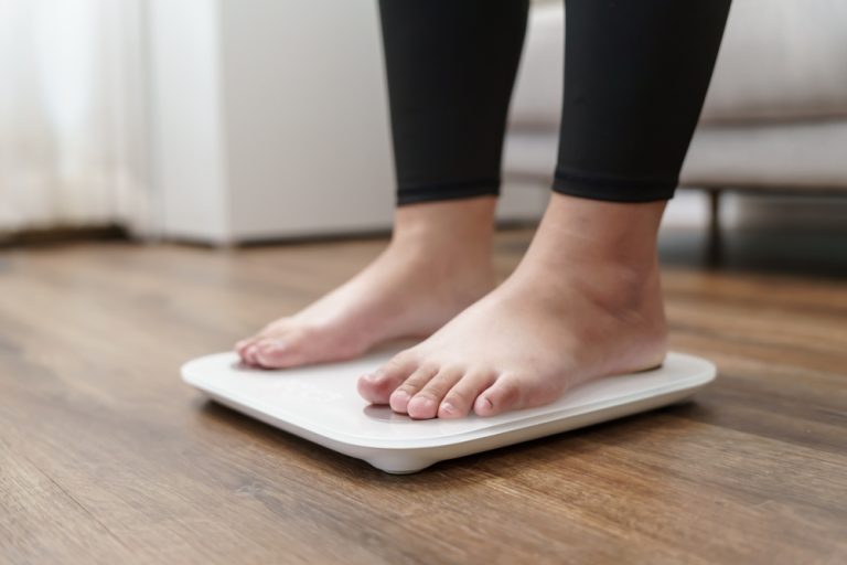 Personne debout sur une balance dans une pièce intérieure.