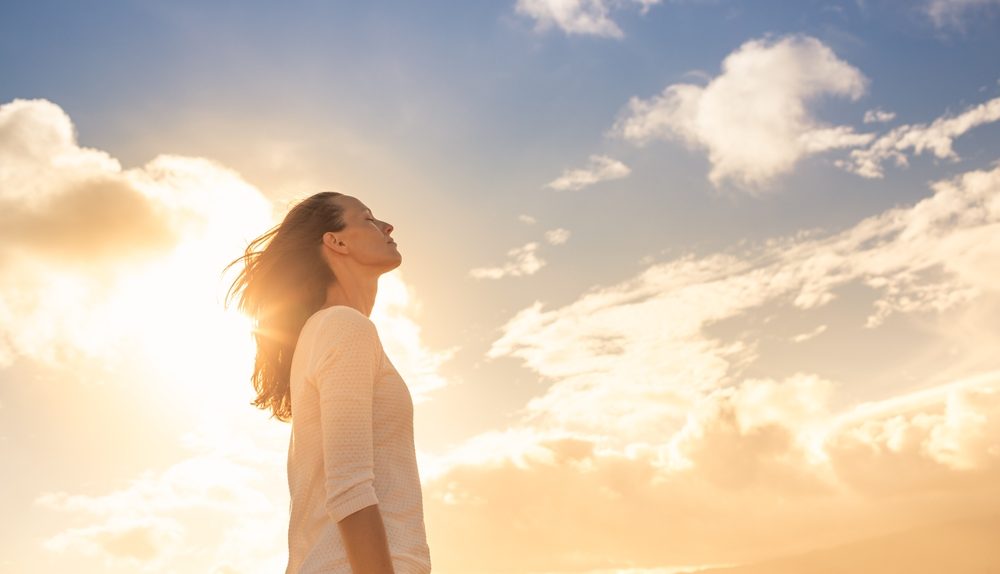 Femme sereine observant un coucher de soleil estival lors d’un épisode de forte chaleur