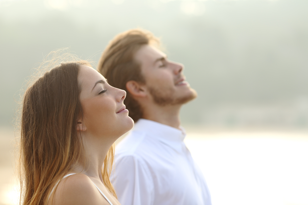 Jeune femme et jeune homme respirant profondément les yeux fermés dans un environnement apaisant.