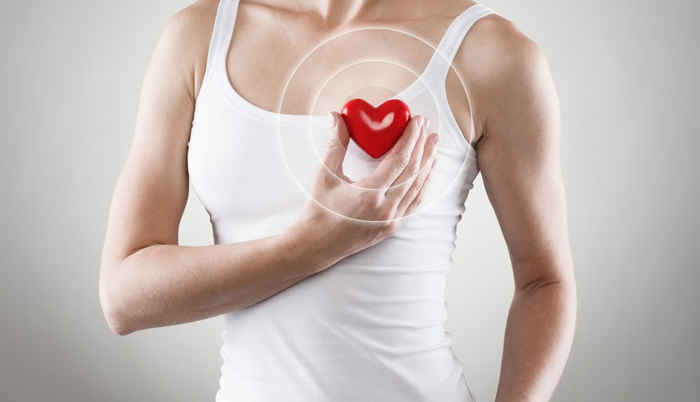 Femme tenant un cœur près de sa poitrine pour illustrer la fibrillation atriale et les troubles du rythme cardiaque
