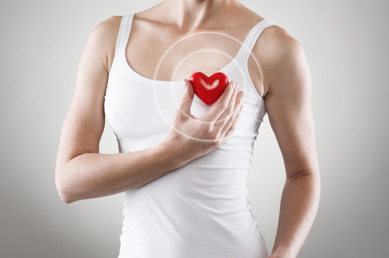 Femme tenant un cœur près de sa poitrine pour illustrer la fibrillation atriale et les troubles du rythme cardiaque