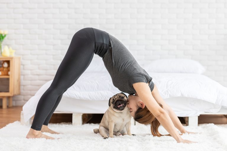 Femme pratiquant le yoga avec son chien pour illustrer les bienfaits des animaux de compagnie sur la santé cardiovasculaire et le bien-être