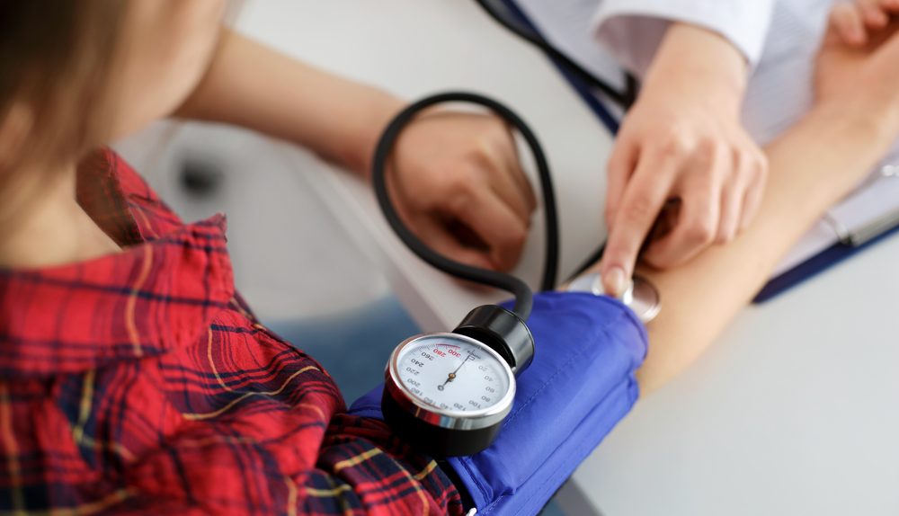 Professionnel de santé prenant la tension artérielle d’une patiente lors d’un contrôle médical.