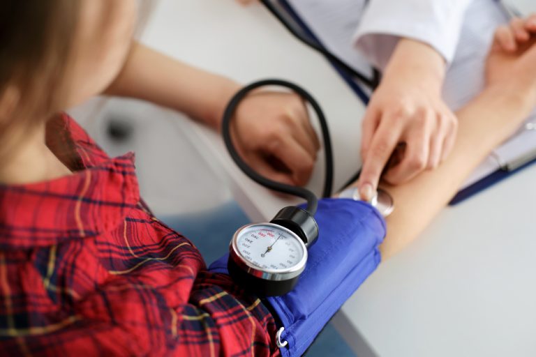 Professionnel de santé prenant la tension artérielle d’une patiente lors d’un contrôle médical.