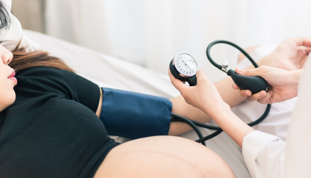Femme enceinte lors d’un contrôle médical avec prise de tension artérielle pendant le suivi de grossesse.