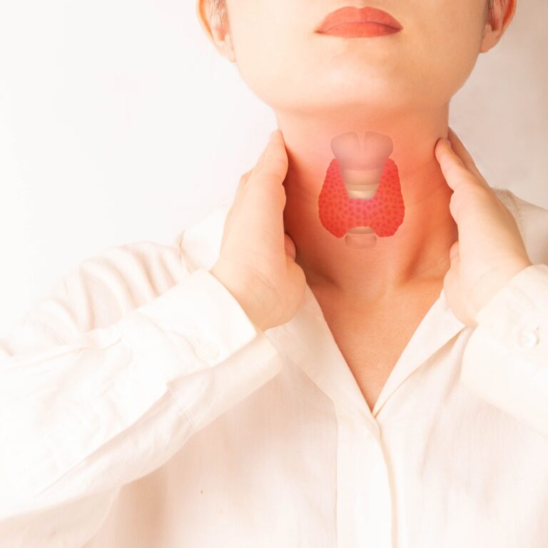 Femme palpant sa gorge illustrant les troubles de la thyroïde, l’hyperthyroïdie et leurs impacts sur la santé cardiovasculaire