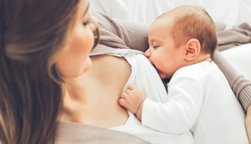 Mère allaitant son bébé dans un moment de tendresse et de proximité illustrant la maternité et le lien parent-enfant.
