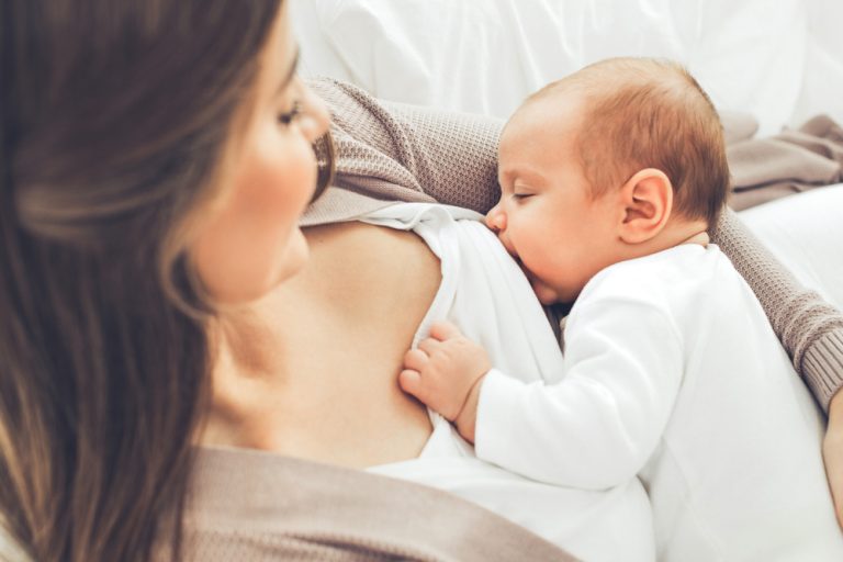 Mère allaitant son bébé dans un moment de tendresse et de proximité illustrant la maternité et le lien parent-enfant.