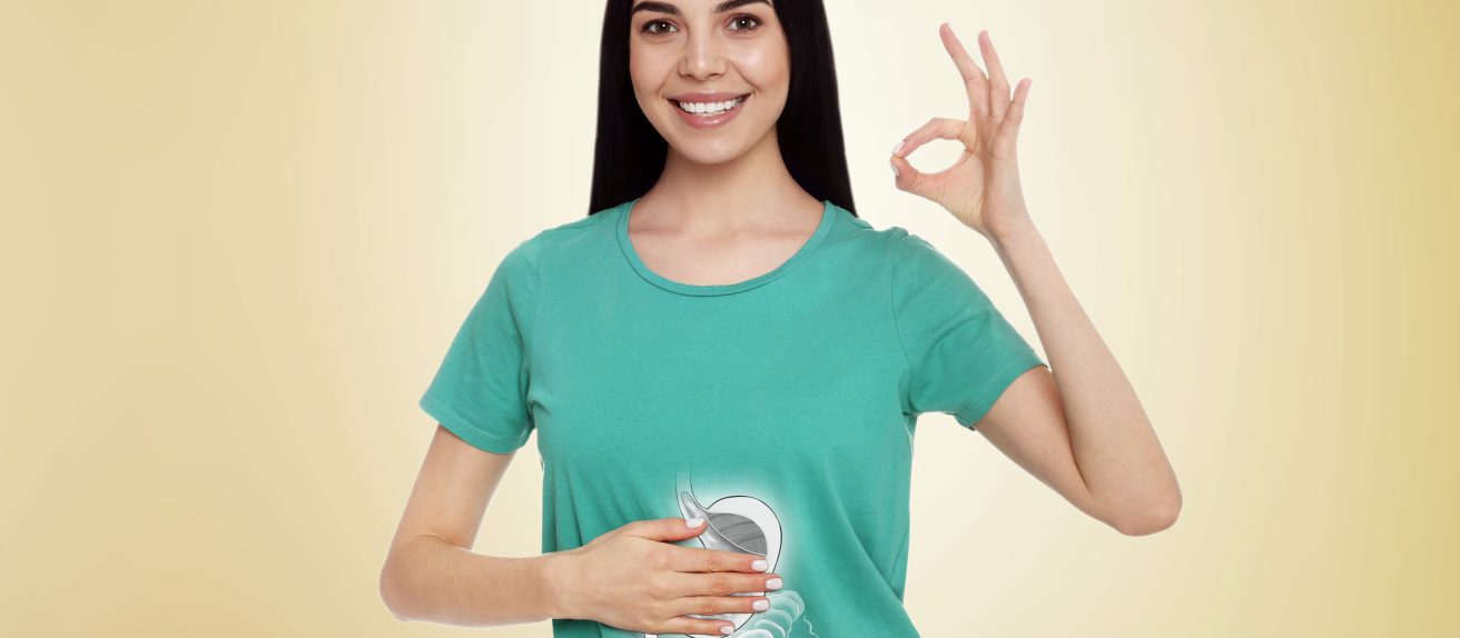 Jeune femme souriante montrant son ventre avec une illustration du système digestif pour représenter la santé intestinale et la digestion.