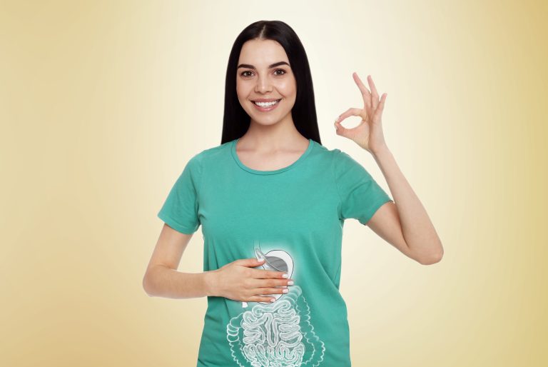 Jeune femme souriante montrant son ventre avec une illustration du système digestif pour représenter la santé intestinale et la digestion.