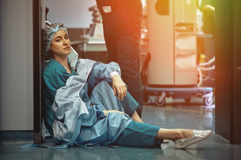 Soignante assise au sol dans un hôpital en état d’épuisement professionnel illustrant le burnout et ses conséquences sur la santé cardiovasculaire