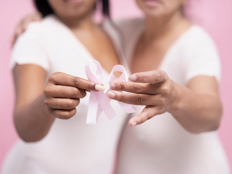 Deux femmes tenant des rubans roses pour sensibiliser au cancer du sein, à l’immunothérapie et aux risques cardiovasculaires associés aux traitements