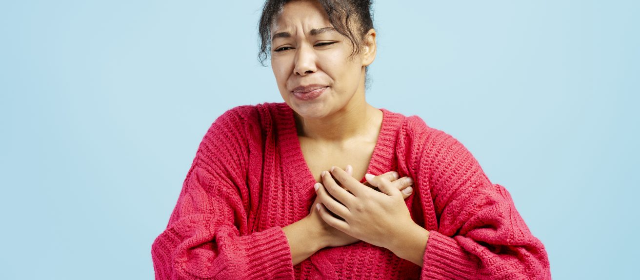 Femme se tenant la poitrine illustrant une douleur thoracique liée à l’angor.