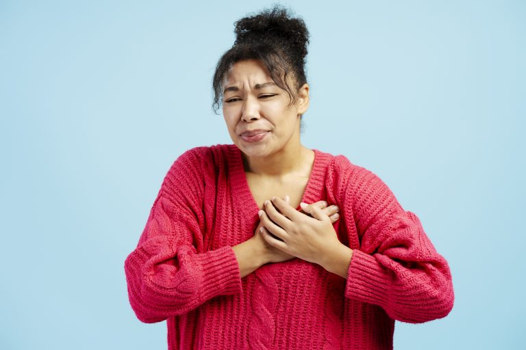 Femme se tenant la poitrine illustrant une douleur thoracique liée à l’angor.