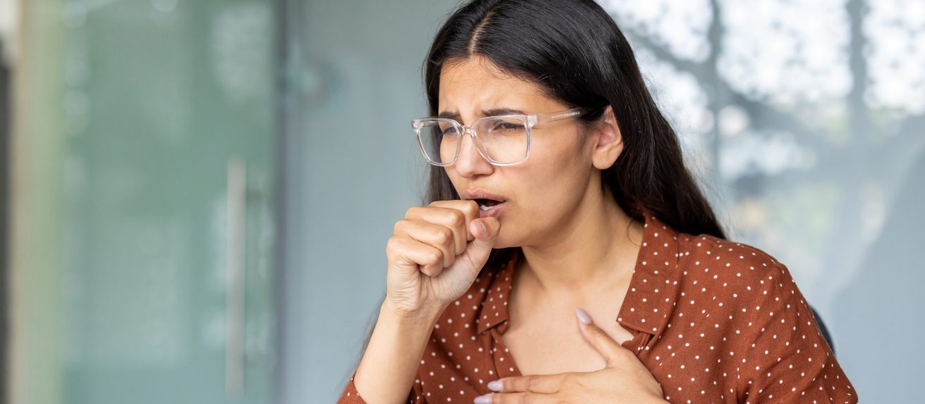 Femme se tenant la poitrine illustrant les symptômes de la cardiopathie hypertensive.