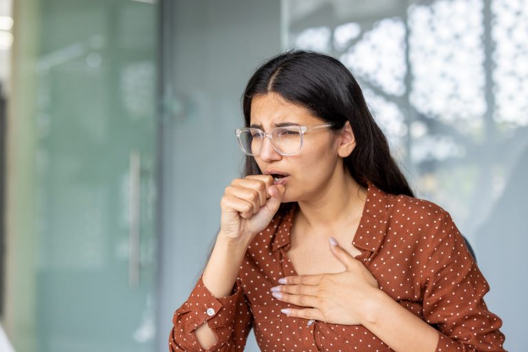 Femme se tenant la poitrine illustrant les symptômes de la cardiopathie hypertensive.