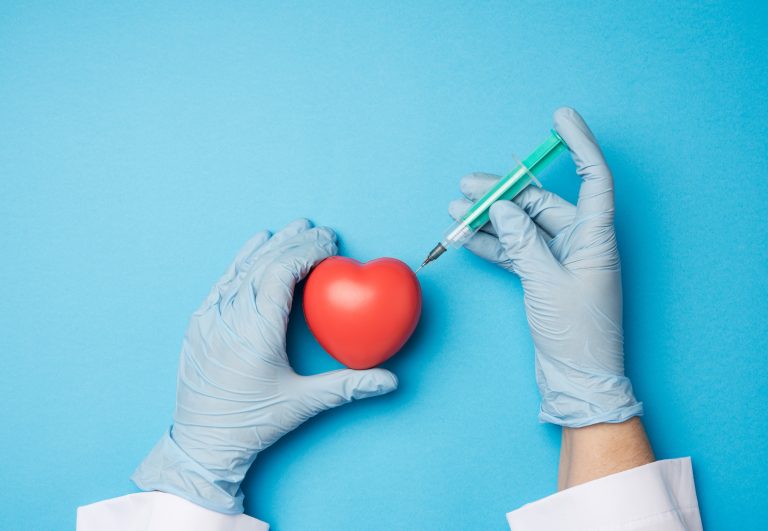 Médecin tenant une seringue près d’un modèle de cœur illustrant une coronarographie