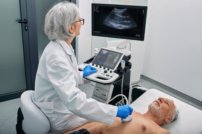 Médecin réalisant une échographie cardiaque transthoracique avec une sonde sur la poitrine d’un patient