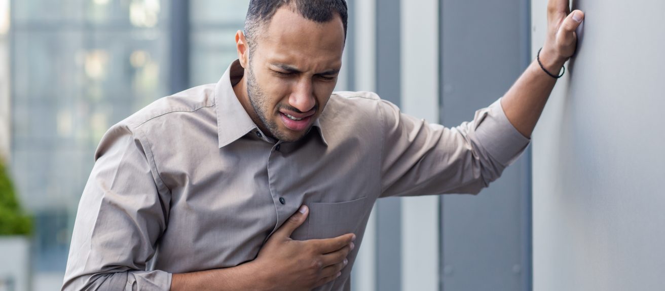 Homme se tenant la poitrine illustrant les symptômes de la fibrillation atriale, trouble du rythme cardiaque.