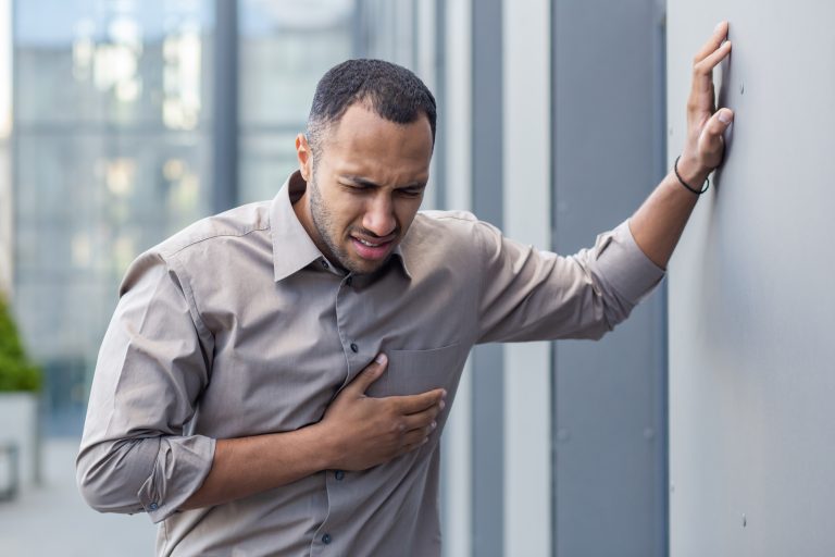 Homme se tenant la poitrine illustrant les symptômes de la fibrillation atriale, trouble du rythme cardiaque.