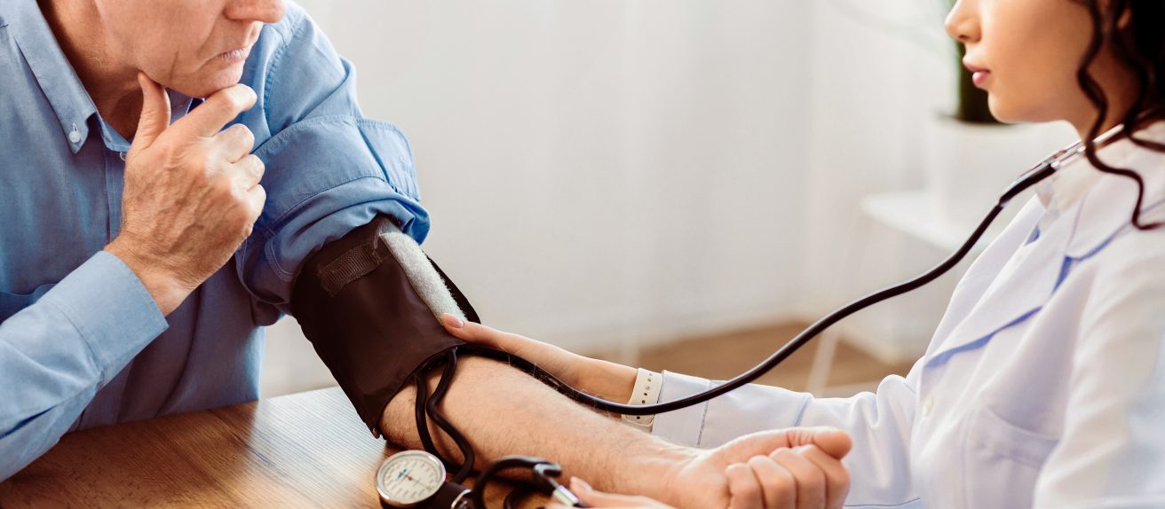 Médecin prenant la tension artérielle d’un patient lors d’une consultation médicale