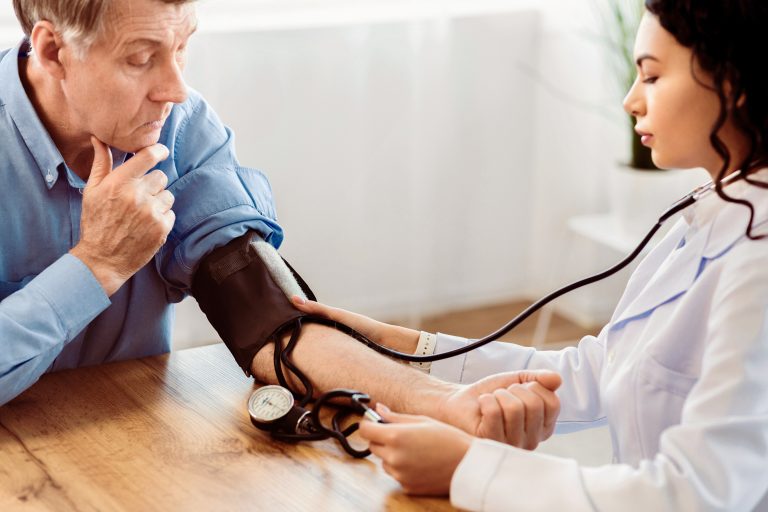 Médecin prenant la tension artérielle d’un patient lors d’une consultation médicale