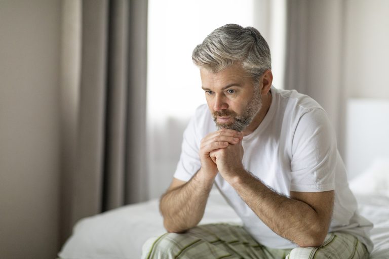 Homme prenant son temps le matin assis sur le bord du lit illustrant la gestion de l’insuffisance cardiaque au quotidien