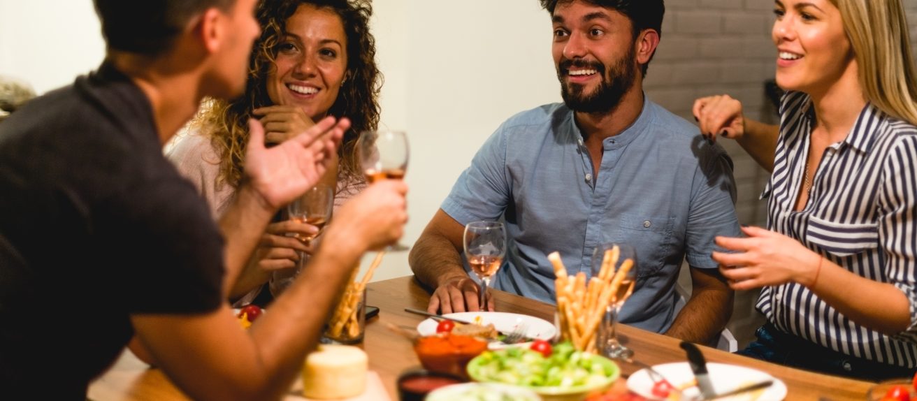 Amis partageant un repas festif avec des verres de vin illustrant la notion de modération pour la santé cardiovasculaire