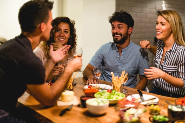 Amis partageant un repas festif avec des verres de vin illustrant la notion de modération pour la santé cardiovasculaire