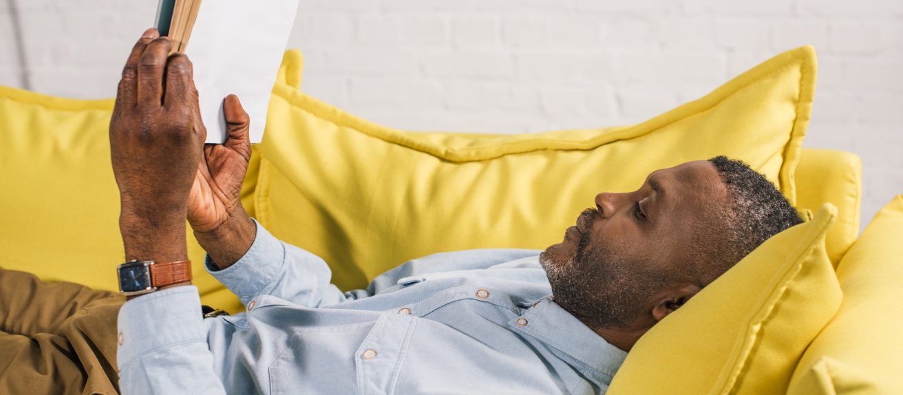 Homme paisible lisant un livre sur un canapé illustrant la récupération progressive après un AVC
