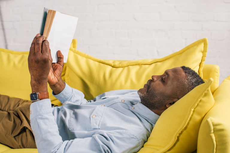 Homme paisible lisant un livre sur un canapé illustrant la récupération progressive après un AVC