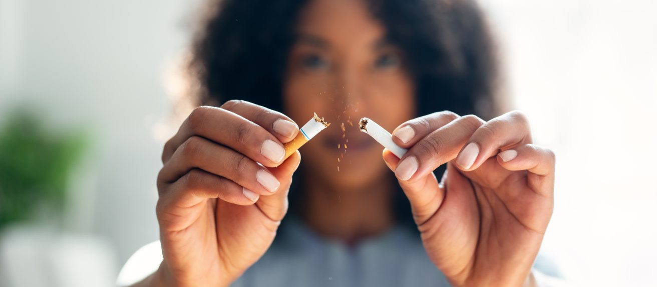 Femme tenant une cigarette illustrant les dangers du tabac sur la santé cardiovasculaire féminine, la contraception, la grossesse et la ménopause