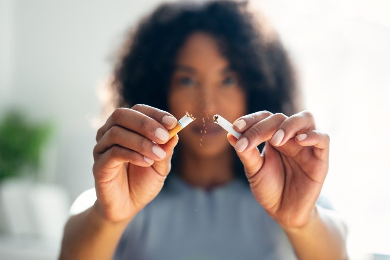 Femme tenant une cigarette illustrant les dangers du tabac sur la santé cardiovasculaire féminine, la contraception, la grossesse et la ménopause