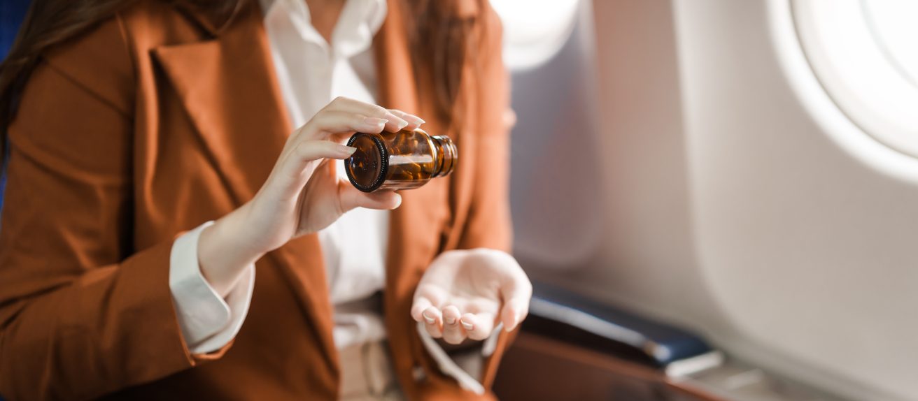 Femme prenant son médicament à bord d’un avion illustrant la gestion d’un traitement cardiovasculaire en voyage