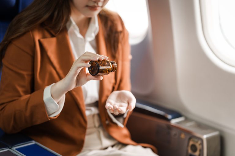 Femme prenant son médicament à bord d’un avion illustrant la gestion d’un traitement cardiovasculaire en voyage