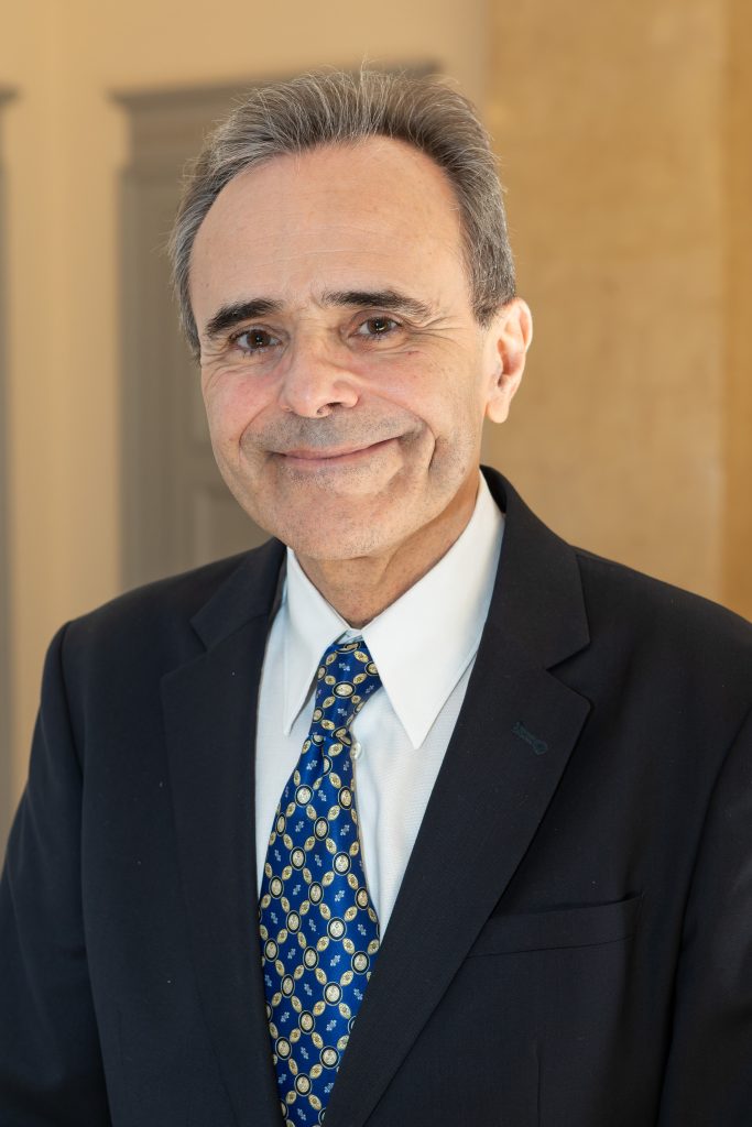 Portrait professionnel d’un homme en costume et cravate lors d’un événement institutionnel lié à la santé et à la recherche.