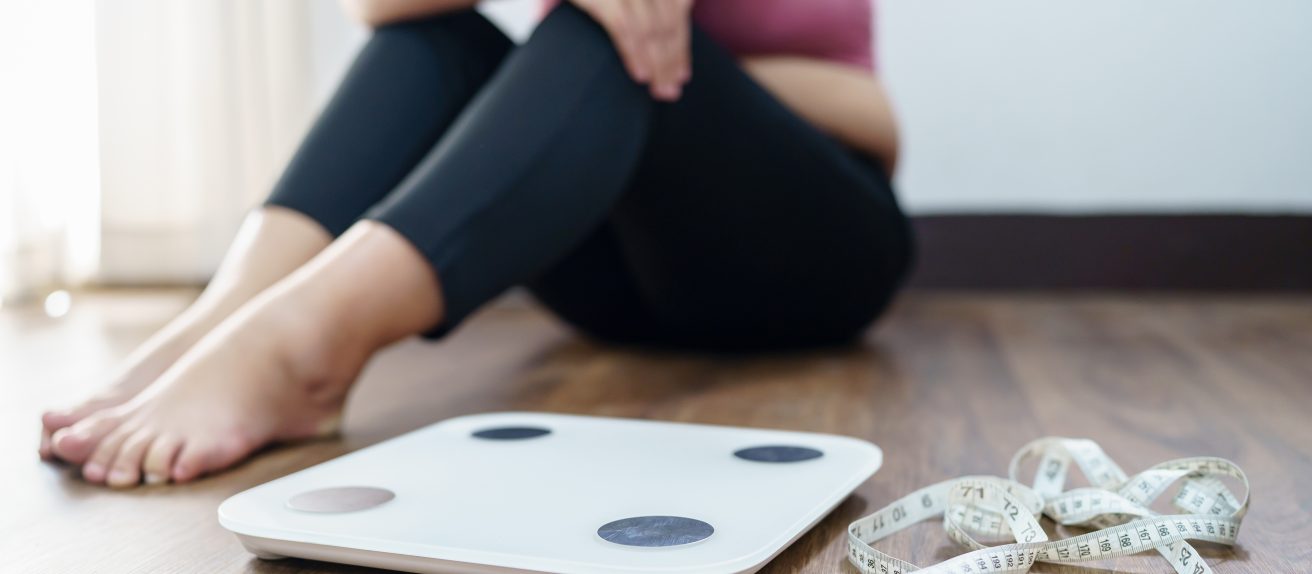 Femme déçue après s’être pesée illustrant les liens entre obésité, hypertension et risque de démence vasculaire