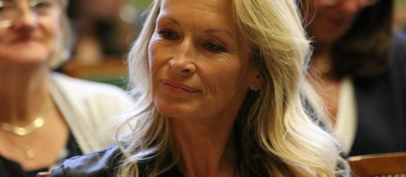 Femme blonde souriante lors d’un événement ou d’une conférence.