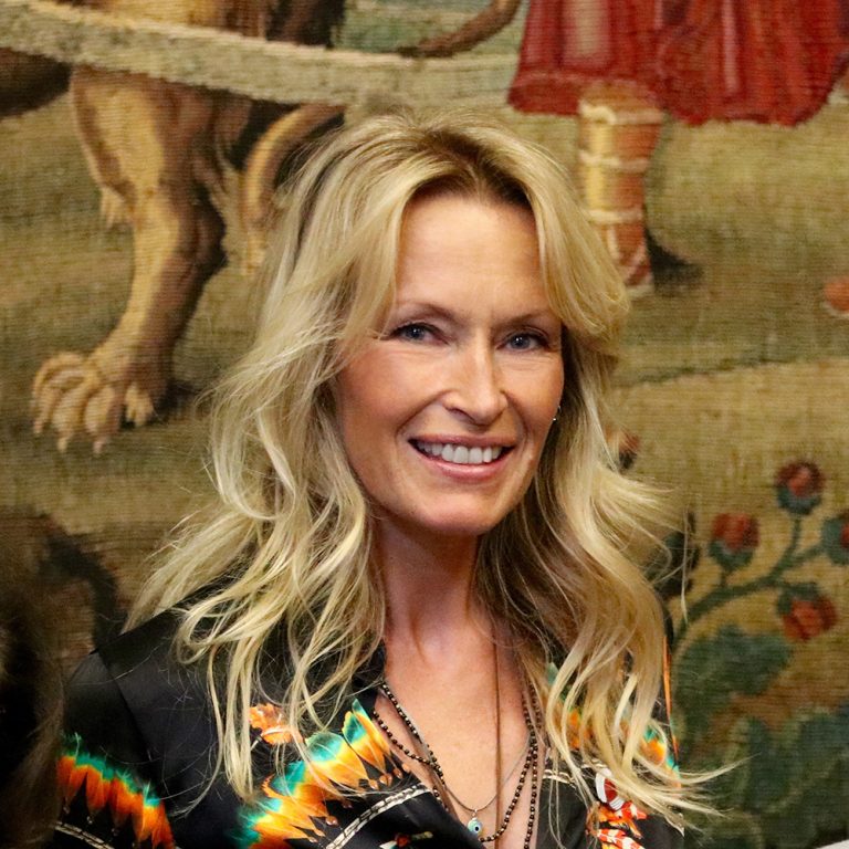 Portrait d’une femme souriante lors d’un événement officiel dans un cadre artistique et institutionnel.