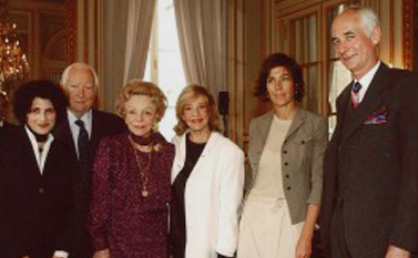 Groupe de six personnes élégamment habillées lors d’un événement officiel.