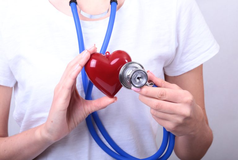 Une personne tient un cœur rouge et un stéthoscope dans ses mains.